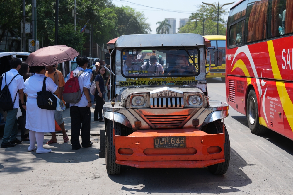 ركاب قرب سيارة جيبني التقليدية الشهيرة في مانيلا، الفلبين. (أ.ب)