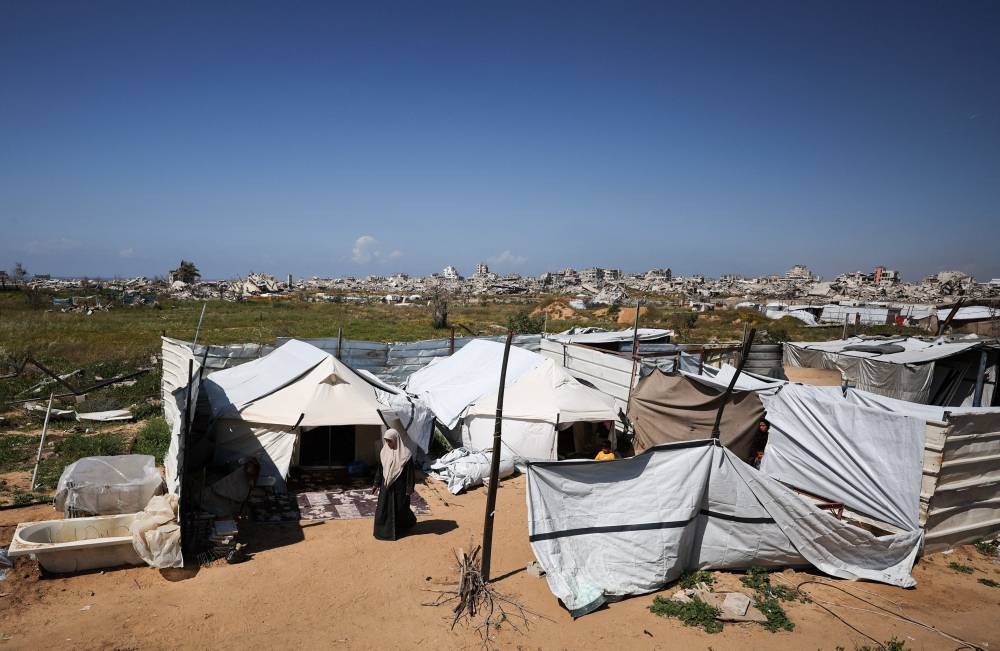 فلسطينية نازحة تقف أمام خيمتها في مدينة غزة (ويترز)