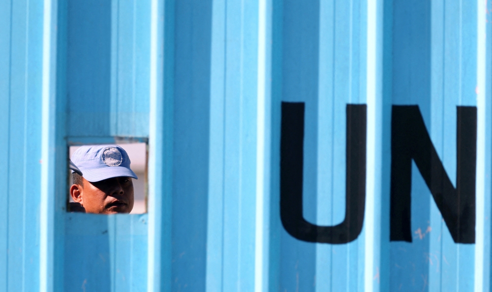 جندي من اليونيفيل ينظر من فتحة في قرية الحولة الحدودية جنوب لبنان (رويترز/صورة أرشيفية)