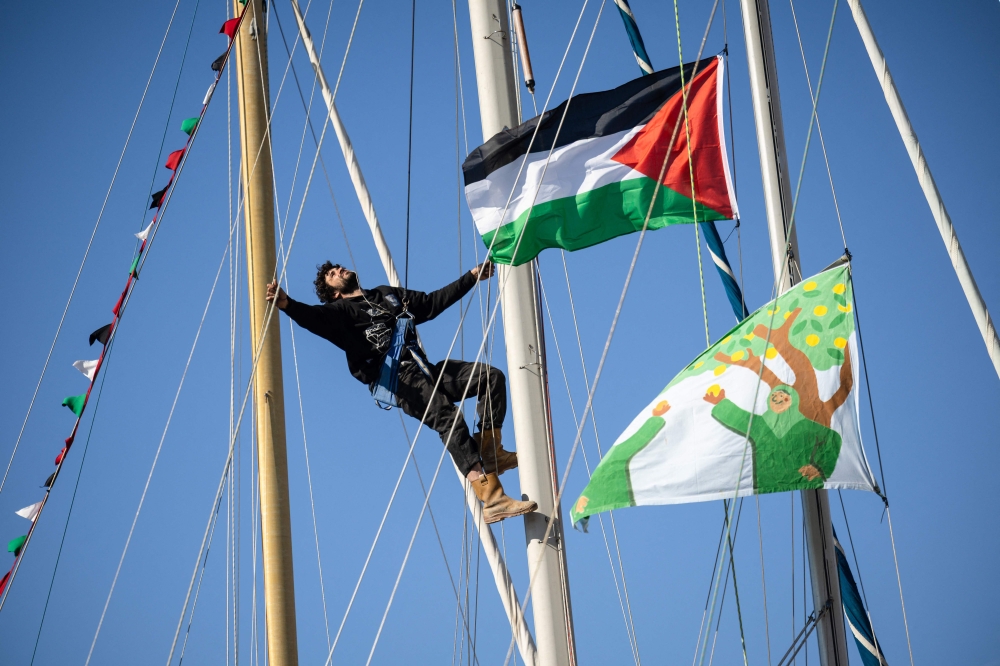 ناشط يتسلق سارية قارب يحمل العلم الفلسطيني في ميناء مرسيليا جنوب فرنسا، (في 4 أبريل 2026 / أ.ف.ب)