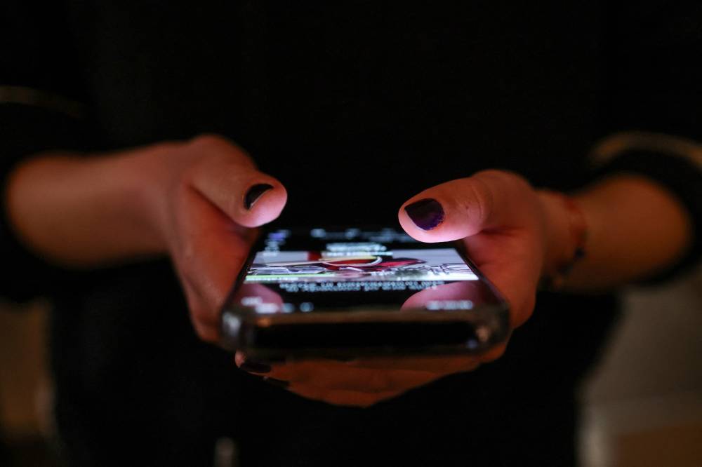 فتاة تتصفح منشوراً على وسائل التواصل الاجتماعي بهاتفها (رويترز)