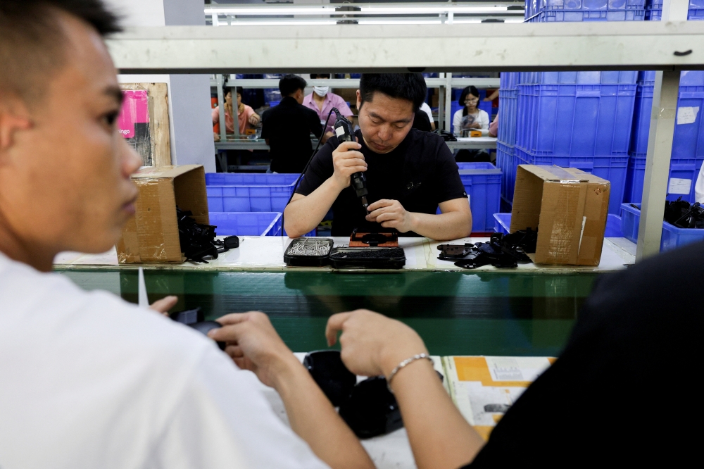 موظفون في خط تجميع حوامل الهواتف الذكية للسيارات في مصنع لملحقات البلاستيك، في دونغقوان، بمقاطعة قوانغدونغ، الصين (رويترز)